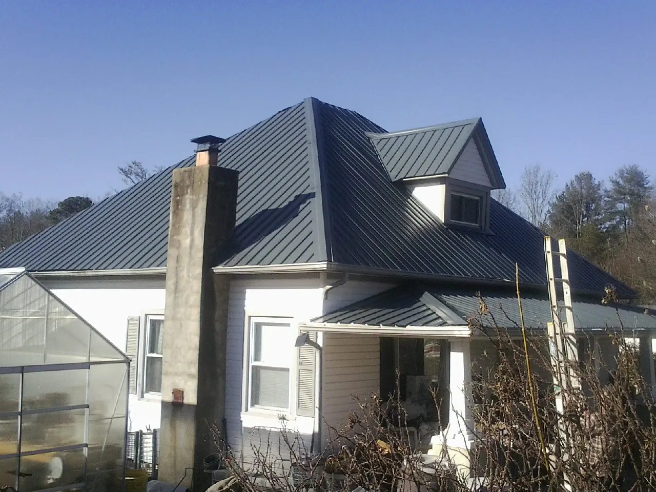 Dark blue standing seam metal roof on a white farmhouse with dormer — Slate & Tile Roof Repair by Roofing Brothers in Sellersville