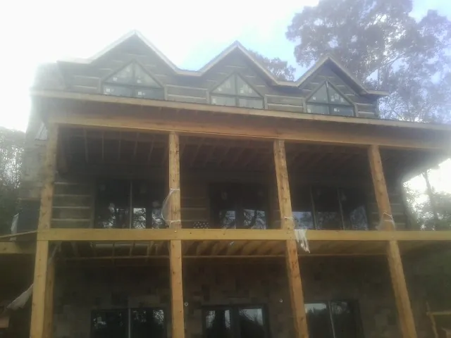 Dormers and porch framing on a large log home under construction — Roof Coating work by our crew in Sellersville