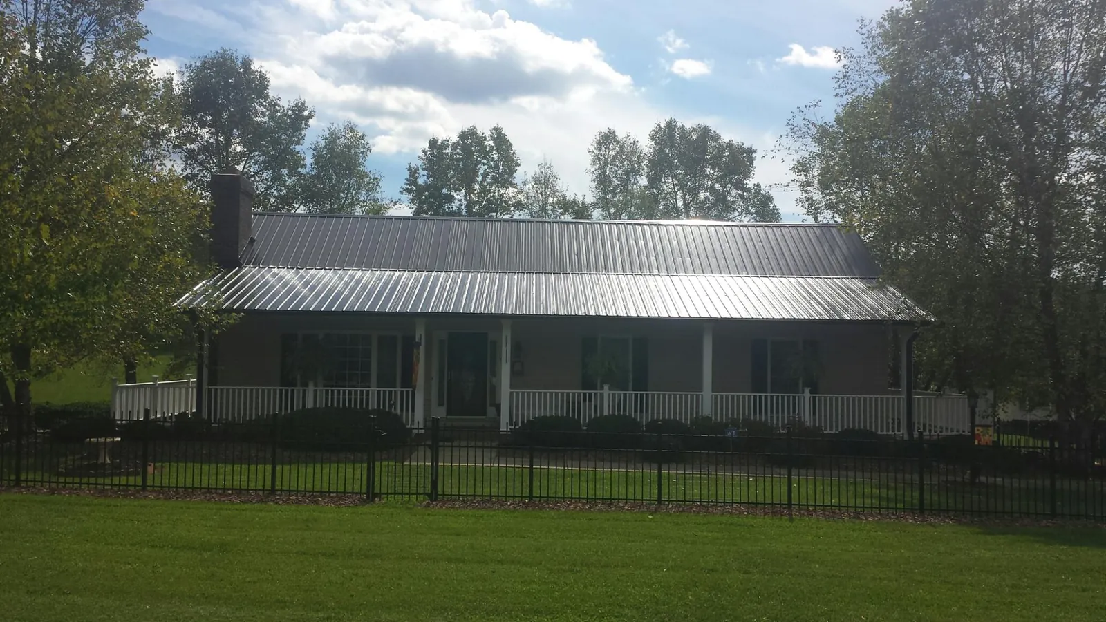 Gray metal roof on a brick ranch with a full width front porch — Gutter Guard Installation work by our crew in Sellersville