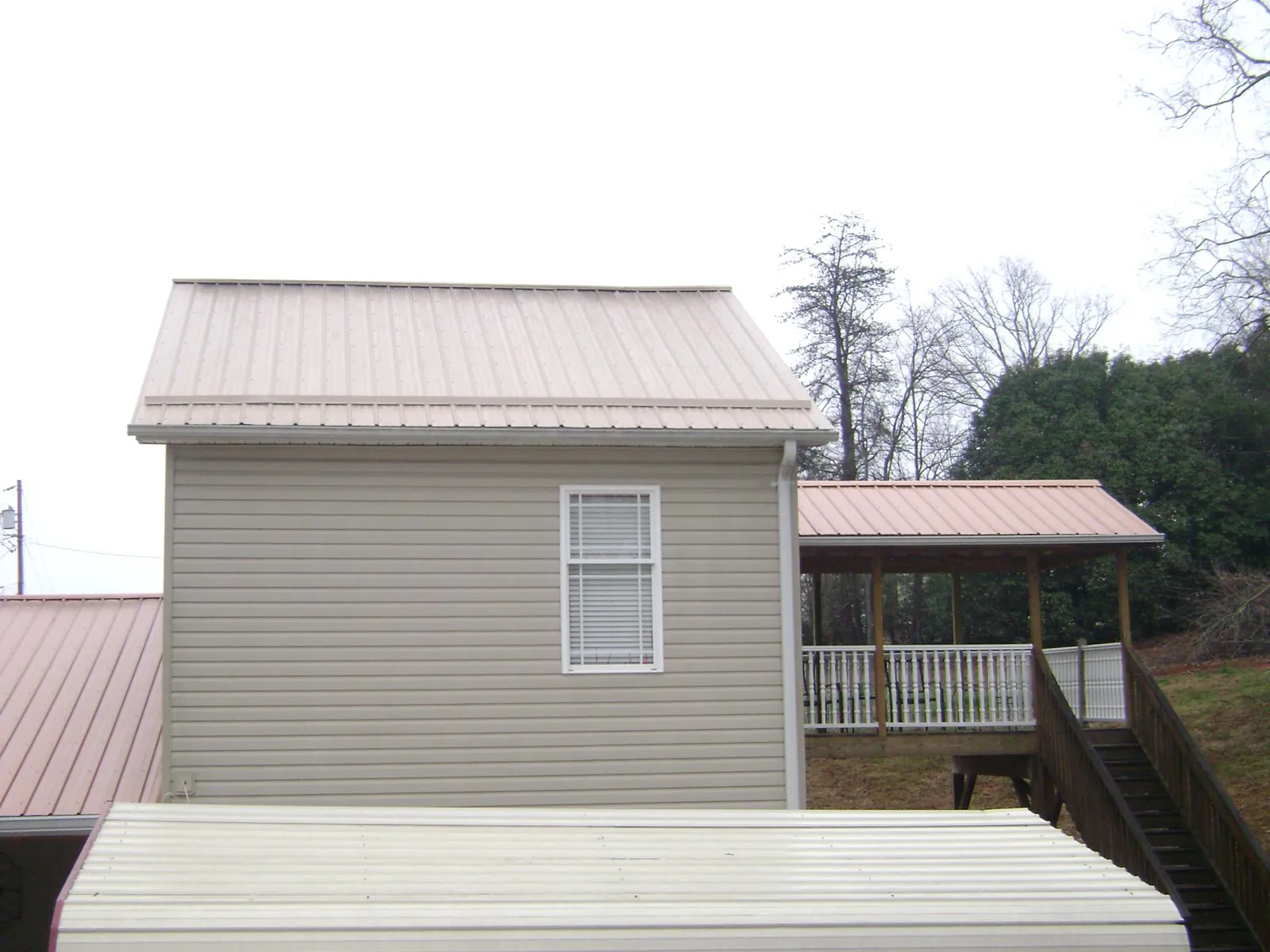 Tan metal roofs on a two story addition and attached porch, from a Roof Replacement job in Sellersville