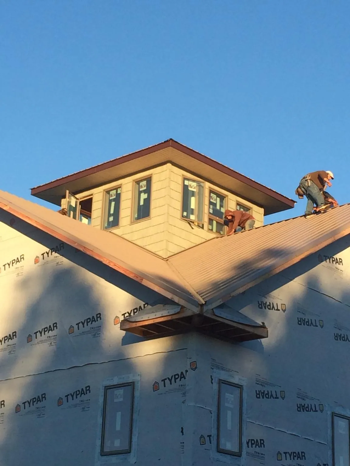 Roofers working around a rooftop cupola on a new metal roof at sunset — Roof Waterproofing in Sellersville by Roofing Brothers
